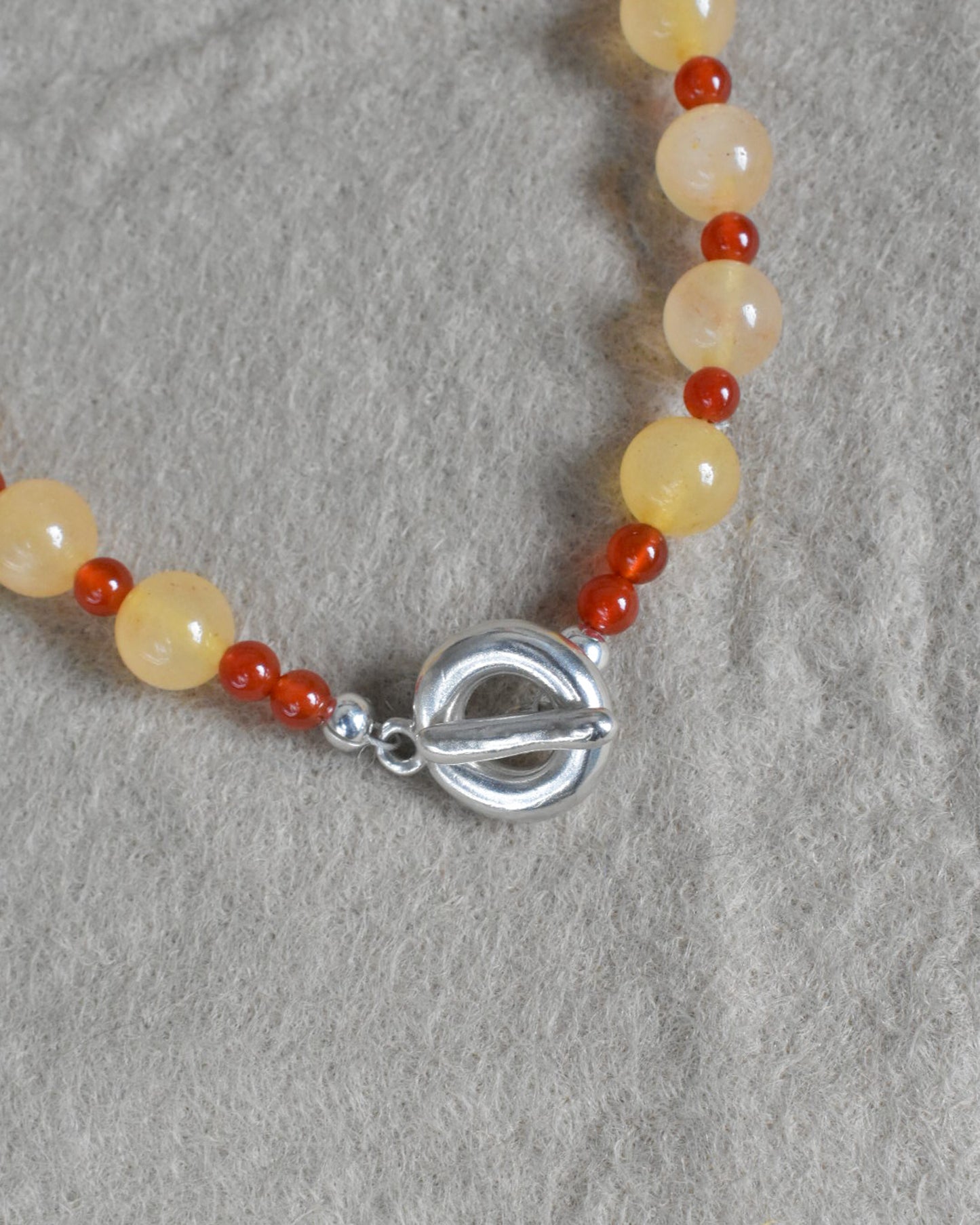 peach melba round smooth colourful beaded necklace with red carnelian and yellow jade. finished with solid silver doughnut shaped clasp.