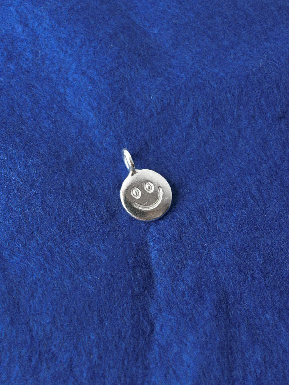 smiley hand carved doodle on a silver shiny disk pendant
