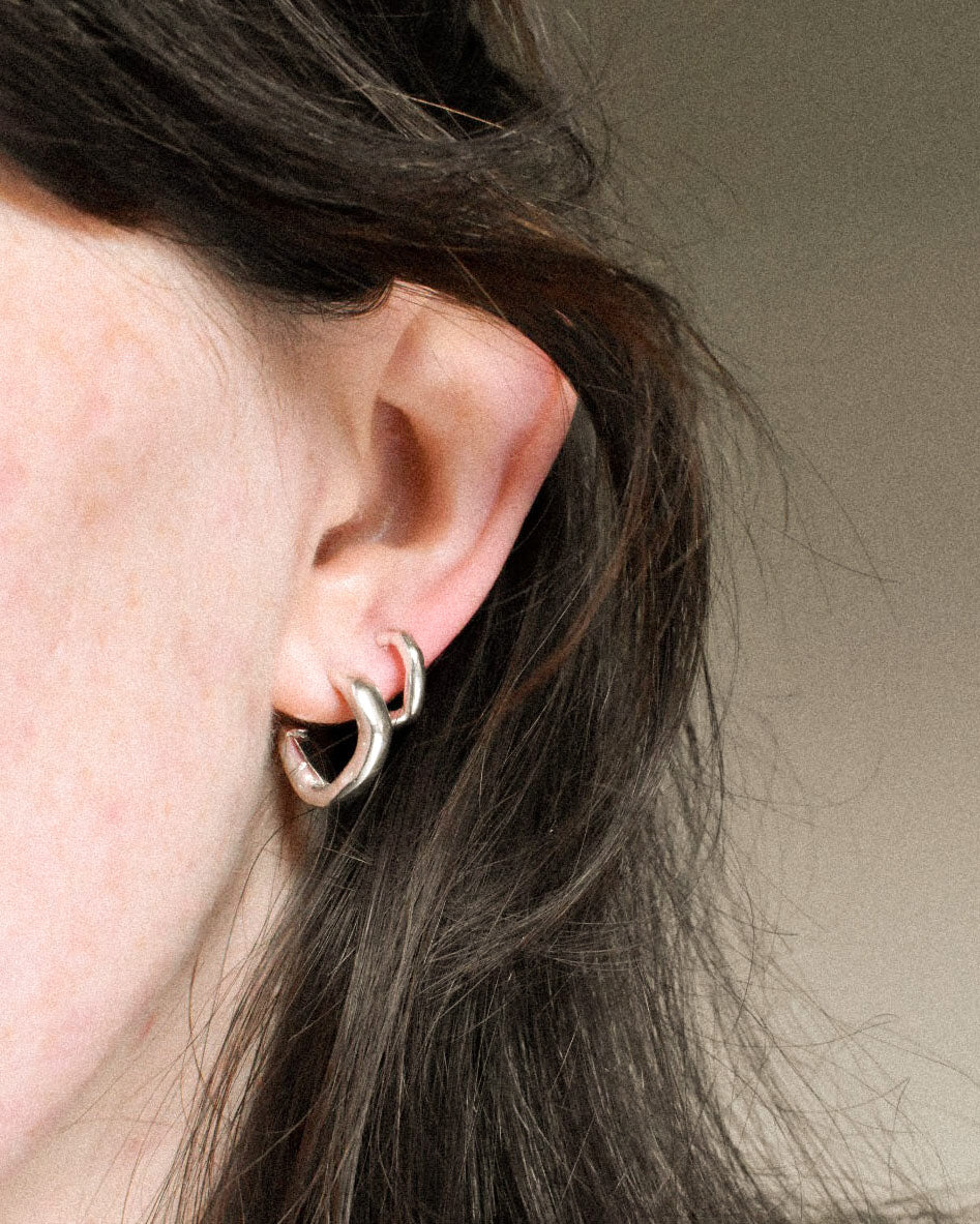 mini delicate thin hoops with organic texture and creases and shapes. handmade in solid recycled silver with push on backs. minimal small hoop earrings. huggy second hoop layer.