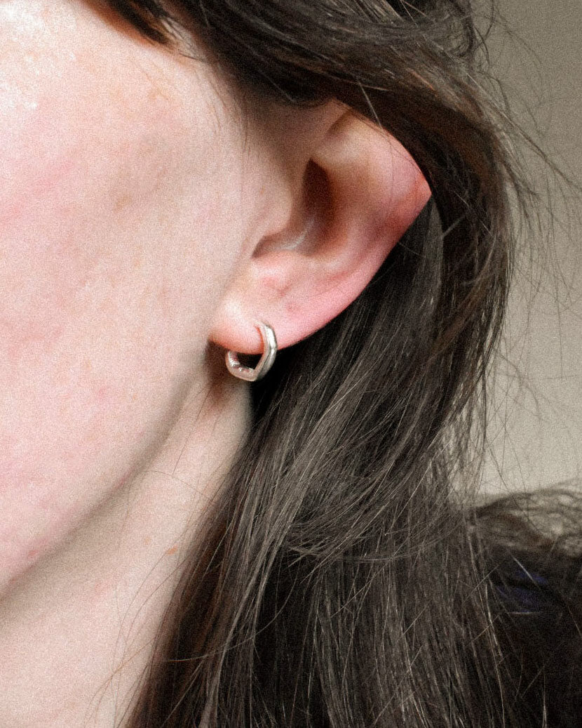mini delicate thin hoops with organic texture and creases and shapes. handmade in solid recycled silver with push on backs. minimal small hoop earrings.