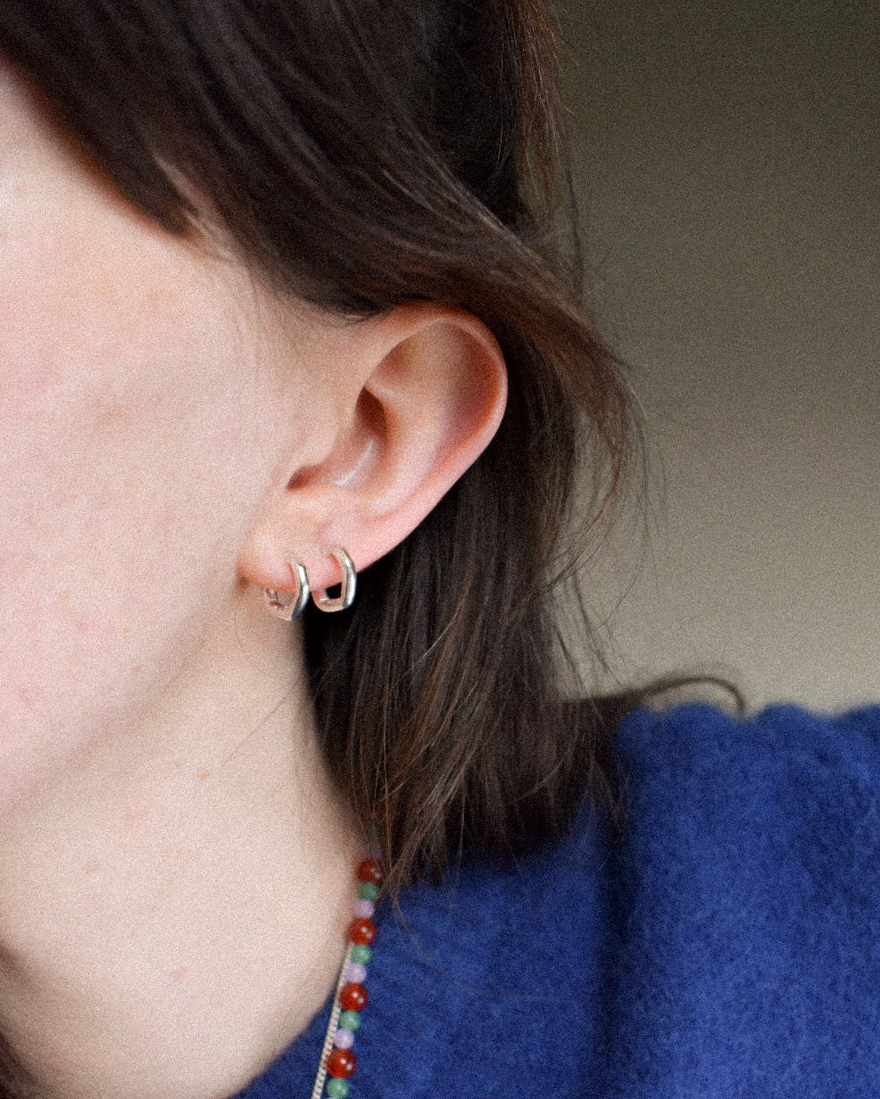 mini delicate thin hoops with organic texture and creases and shapes. handmade in solid recycled silver with push on backs. minimal small hoop earrings.
