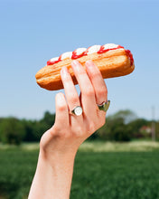 Load image into Gallery viewer, a hand holds a cream doughnut cake in the countryside wearing a blank round eco silver signet ring and heart shaped ring.
