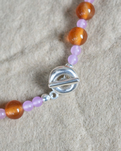 beaded necklace made of colourful stones and solid recycled silver doughnut toggle clasp. the necklace is orange and lilac purple with carnelian and lilac dyed jade.
