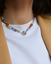 Load image into Gallery viewer, close up of woman wearing white t shirt and fun necklace. colour party beaded necklace, bright rainbow stone and glass beads. blue jade, agate, carnelian, rhodonite. finished with solid recycled silver doughnut toggle clasp.
