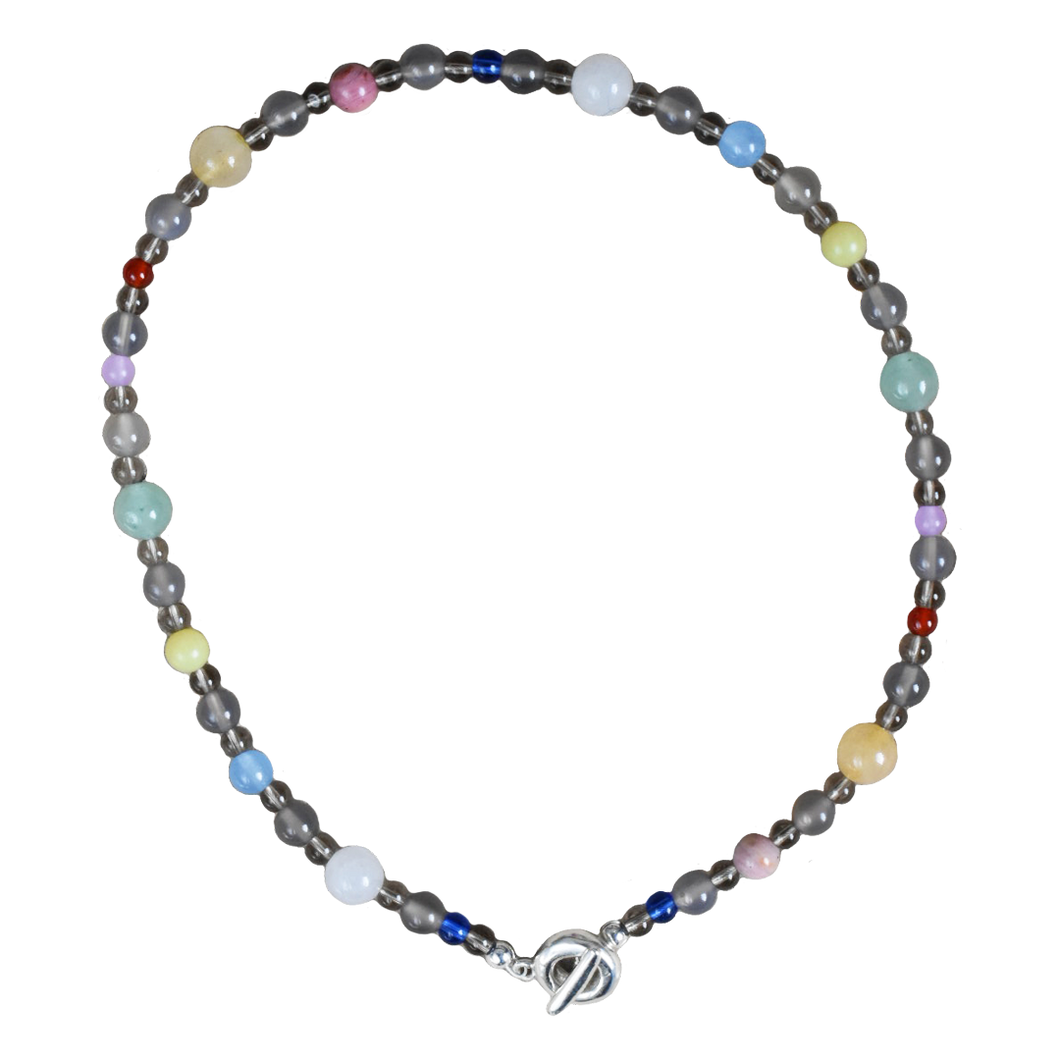 a colourful beaded necklace in a neutral brown grey base with coloirful stone and glass beads scattered. blue jade, agate, carnelian, aventurine. finished with solid recycled silver doughnut toggle clasp.