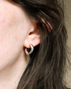 woman wearing solid recycled silver hoop earrings with organic shapes, creases and texture.