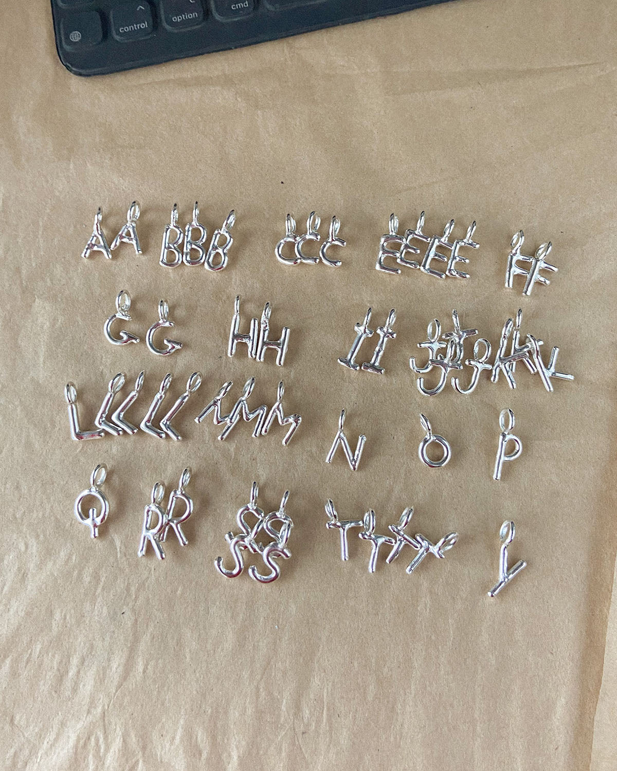recycled silver hand moulded wobbly alphabet initial charms with organic texture